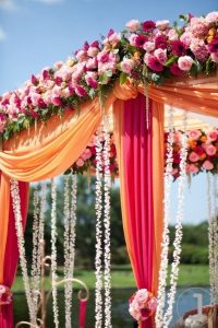 Cylindrical shaped floral decor in a backdrop of orange flowers set by experienced wedding managment company named Kiyoh