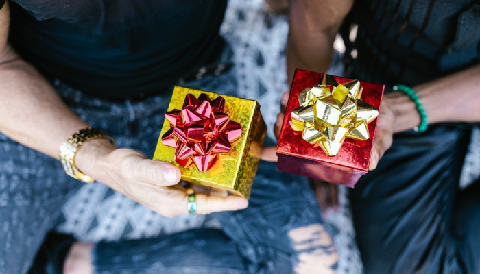 Two persons sitting together with gift boxes on their hands.