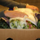 A person (face not seen) is packing bunches of flowers inside a carton getting it ready for shipping.